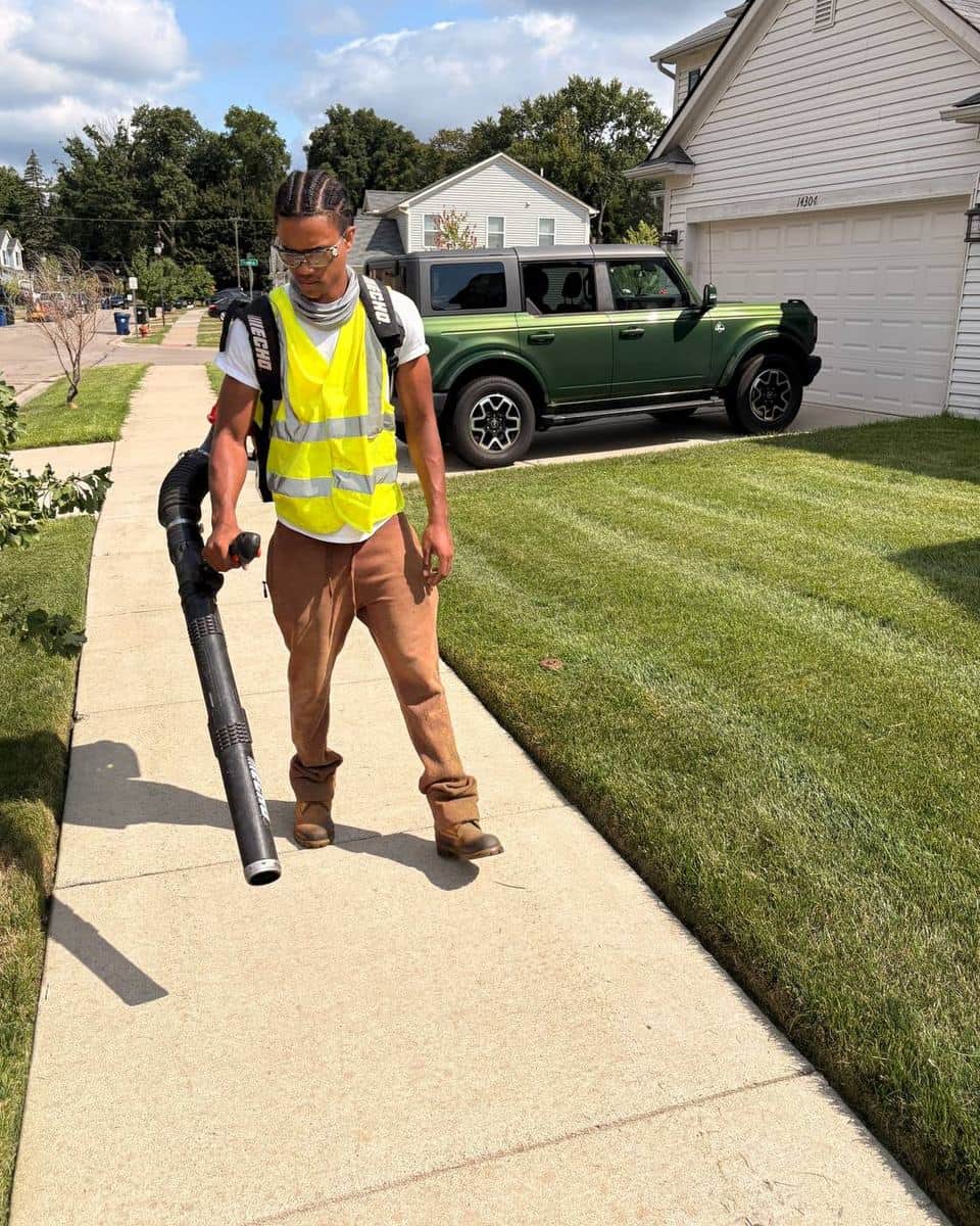 Keonte Woolf, owner of Woolfman Lawn Services, clearing a sidewalk in metro Detroit